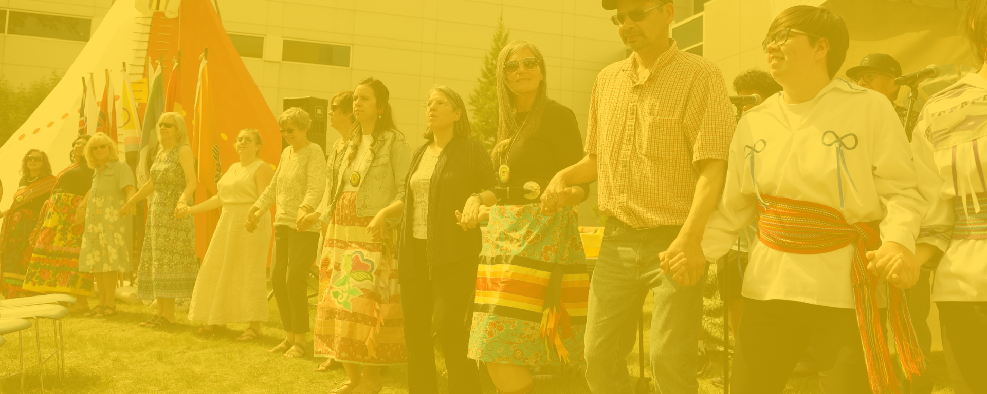 group doing round dance in front of tipi with yellow overlay