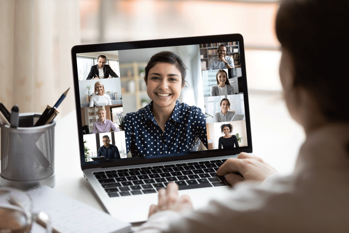 Woman sitting at a table with a laptop open to a virtual conferencing screen