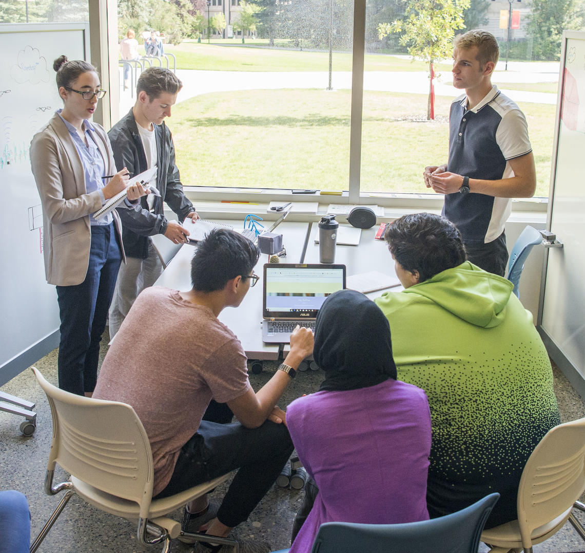 People gathered in a classroom in the TI building, working collaboratively with whiteboards and screens