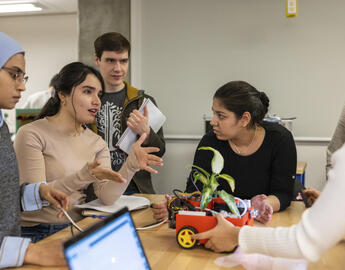 A group of students talking around a table in an engineering class.